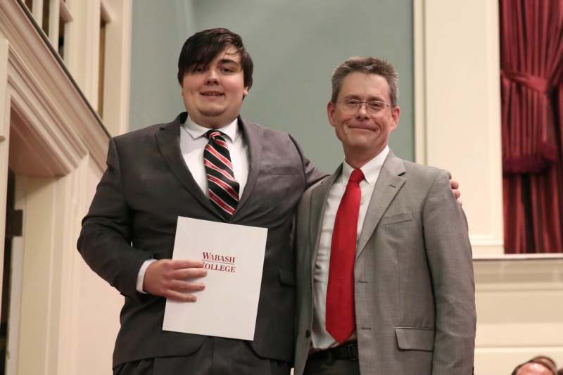 a man in a suit holding a paper with a man in a red tie