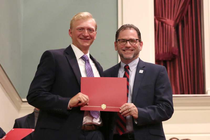 two men in suits holding a red certificate