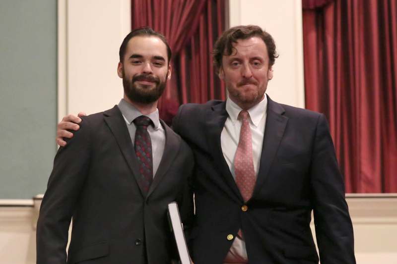 two men in suits posing for a picture