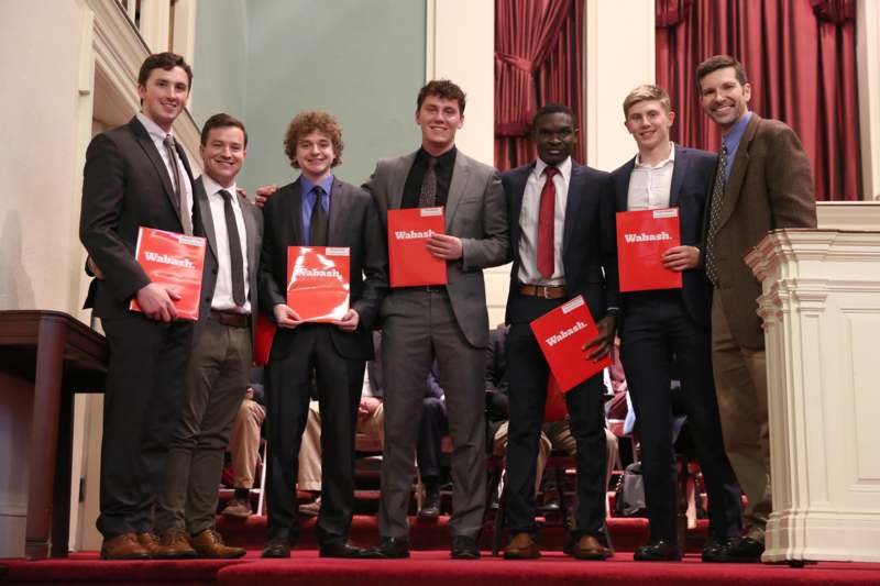 a group of men holding red folders