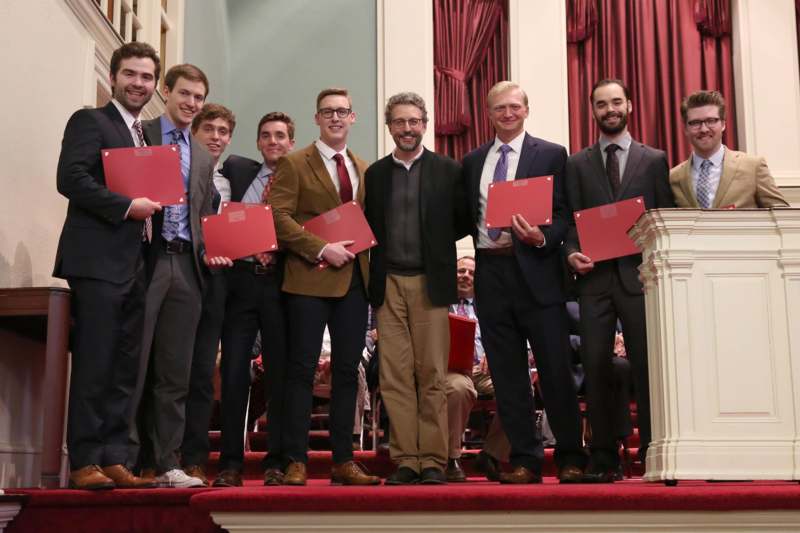 a group of men holding red folders