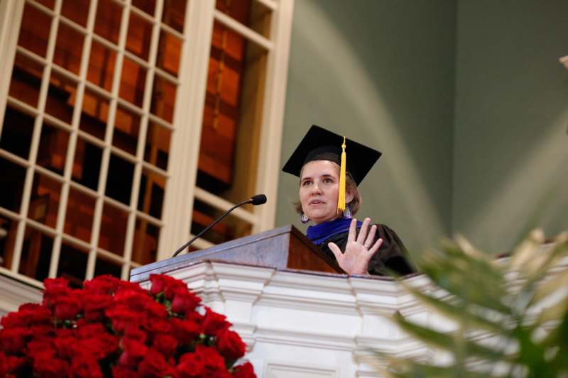 a woman in a graduation cap and gown standing at a podium