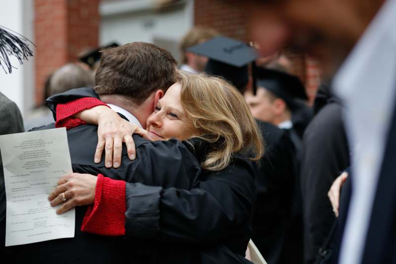 a woman hugging a man in graduation gowns