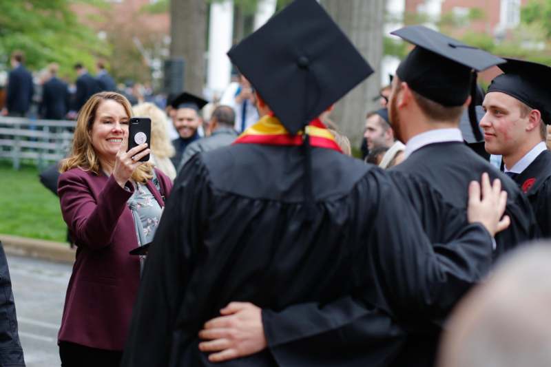 a woman taking a picture of a man in graduation gowns