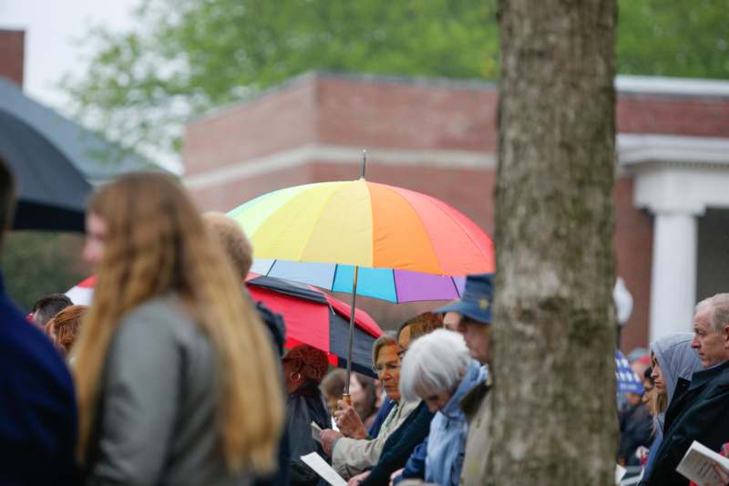 a group of people under a rainbow colored umbrella
