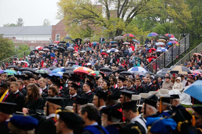 a group of people in graduation gowns holding umbrellas