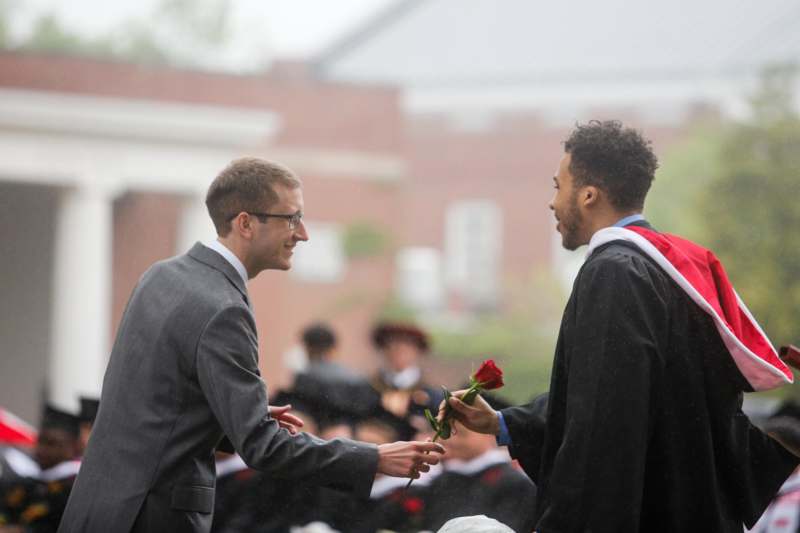 a man giving a rose to another man