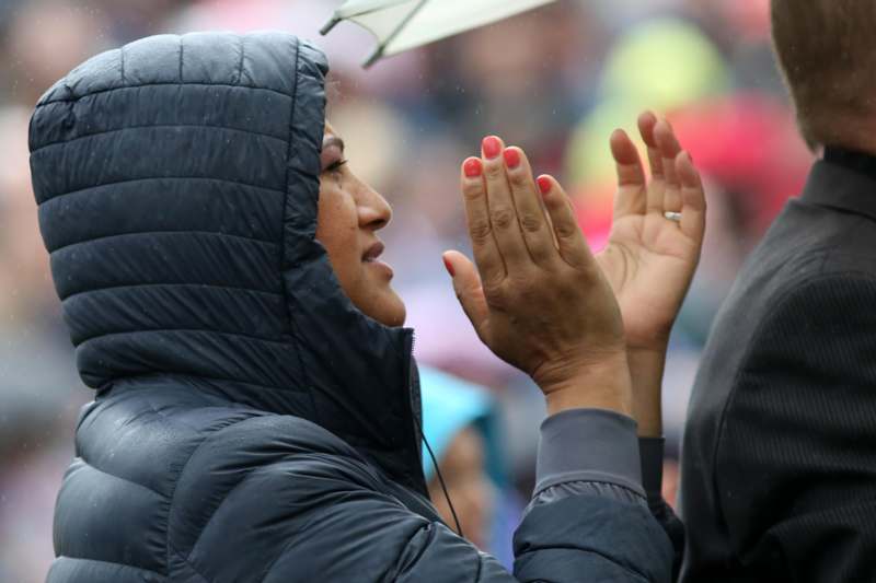 a woman in a black coat with a hood and hands raised