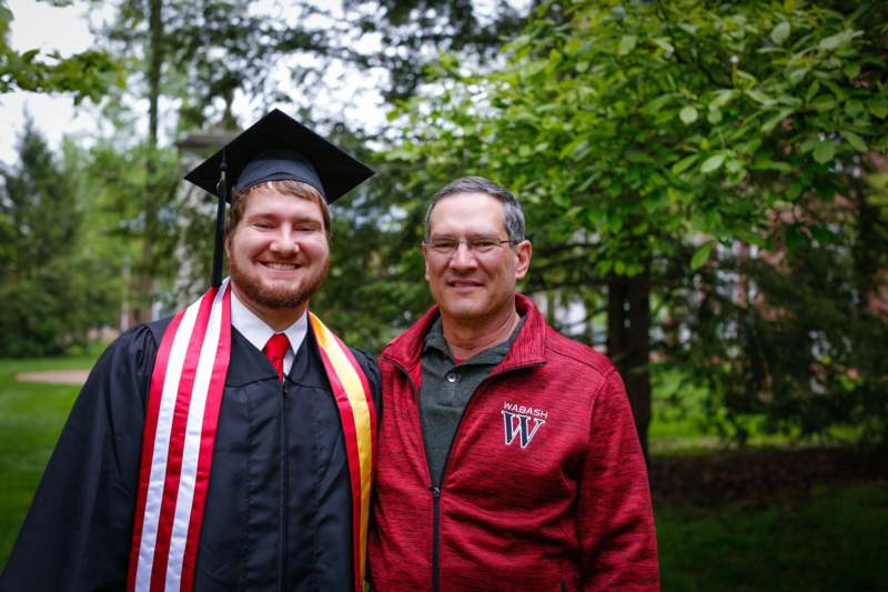 a man in a cap and gown standing next to a man in a red and white shirt