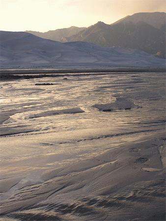 a sandy area with mountains in the background