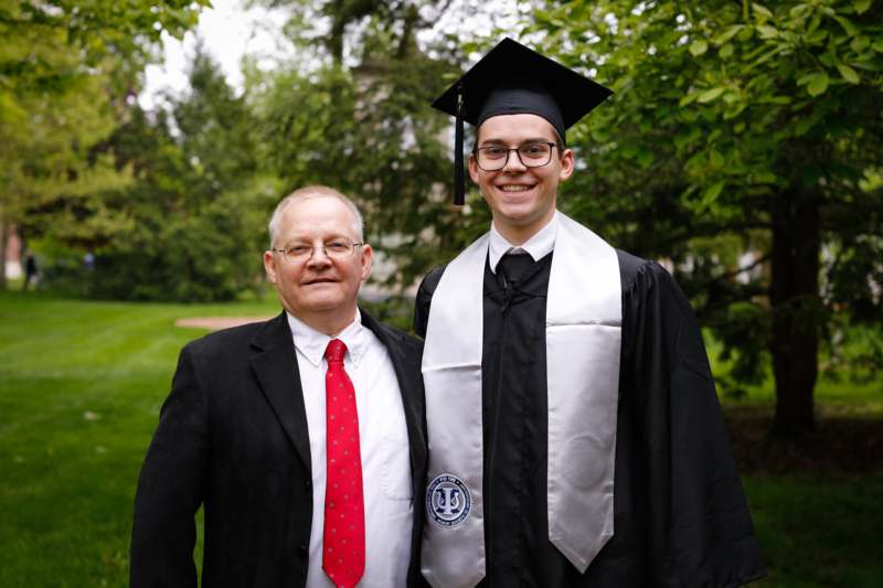 a man in a cap and gown standing next to a man in a suit