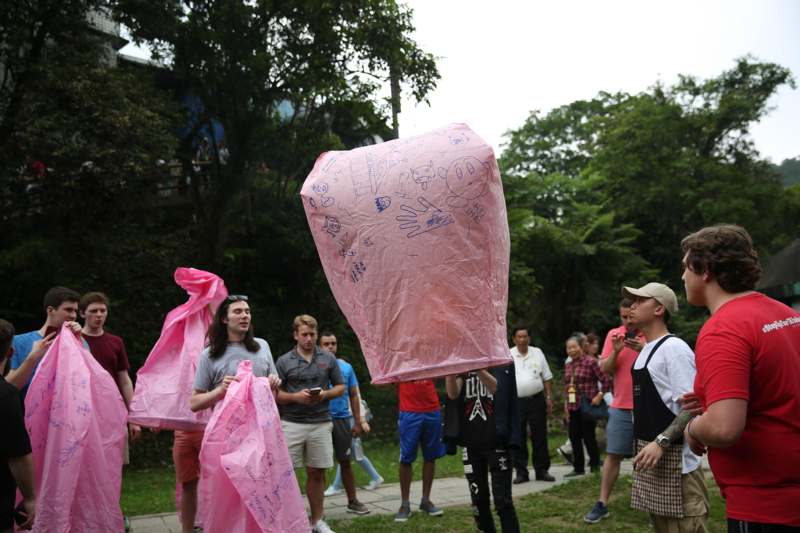 a group of people holding up a large pink bag