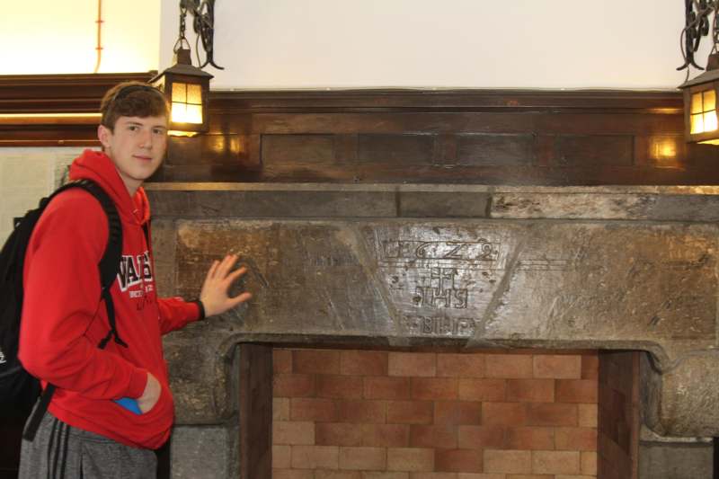 a man standing next to a stone fireplace