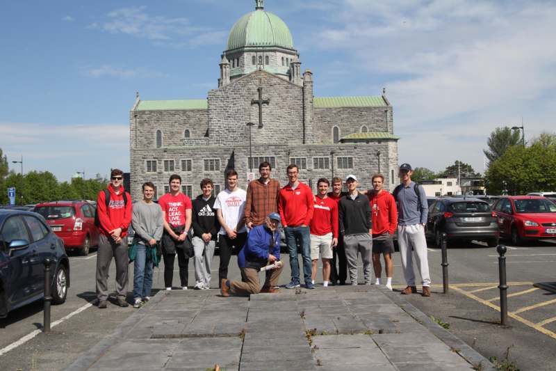 a group of people posing for a photo in front of a stone building