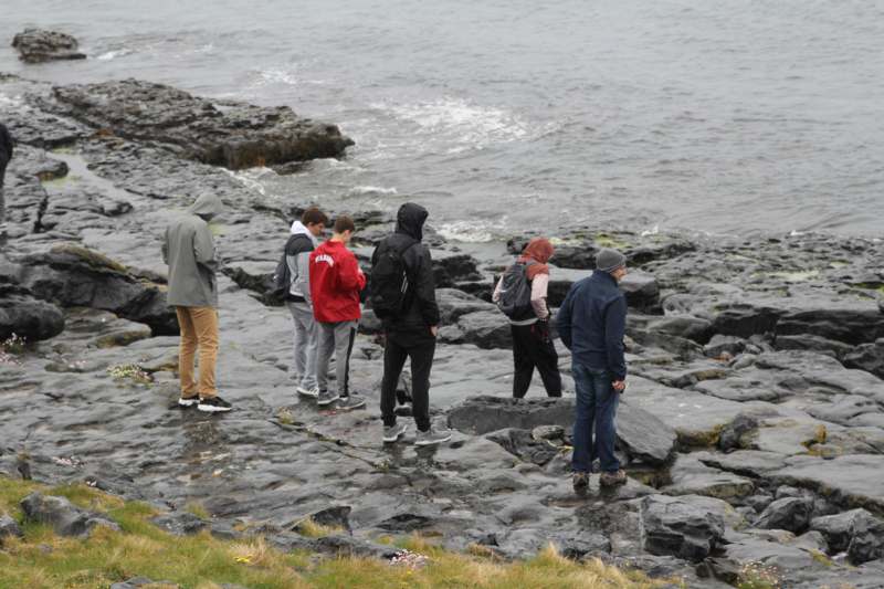 a group of people standing on rocks by the water