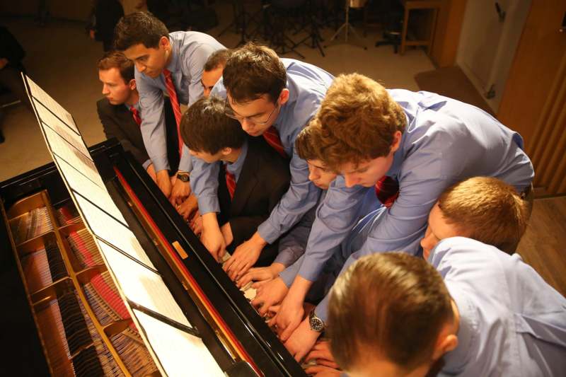 a group of men in a row playing piano