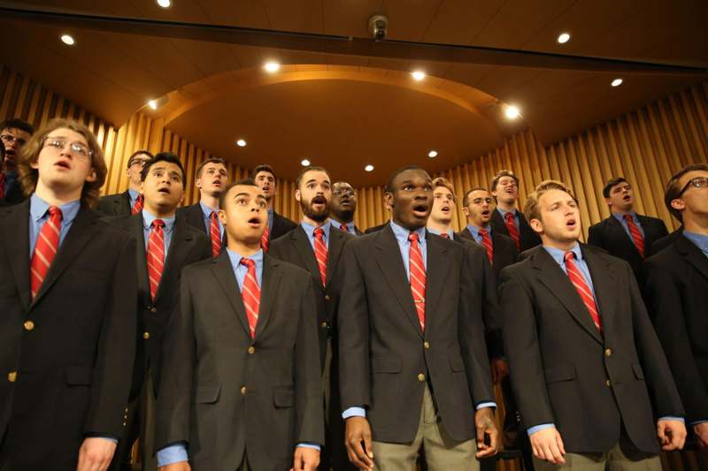 a group of men wearing suits and ties singing