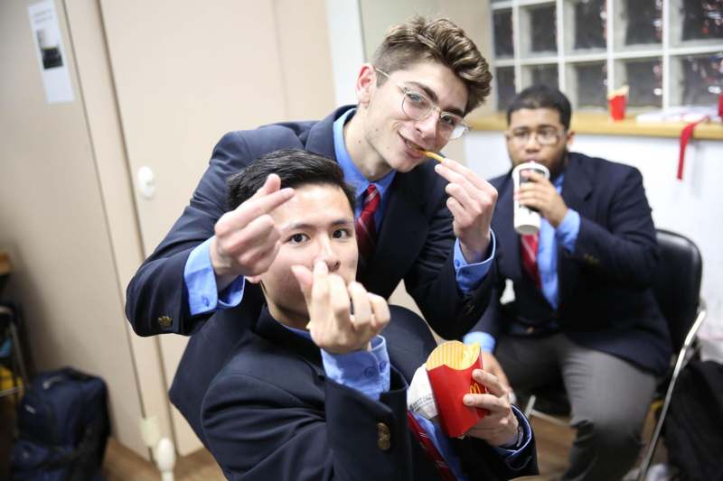 a group of men in suits eating and posing for the camera