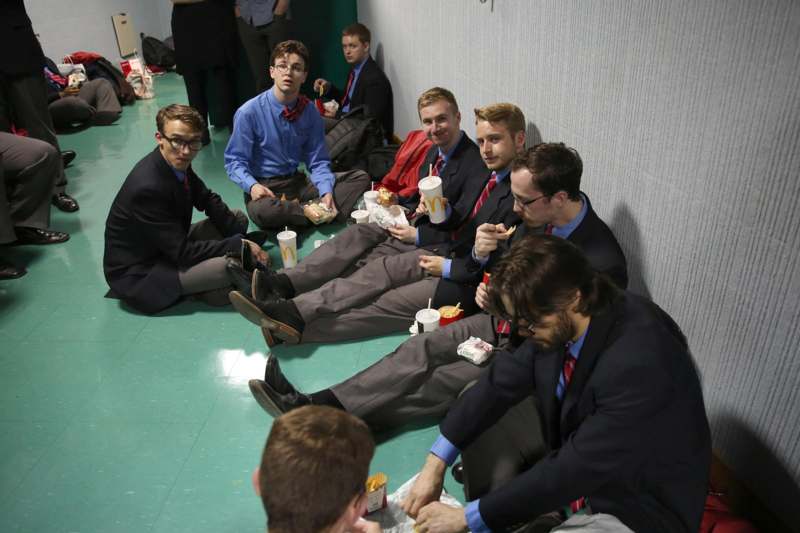 a group of men sitting on the floor eating fast food