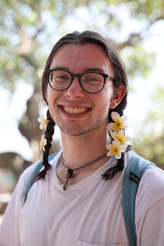 a man with braided hair and flowers in his hair