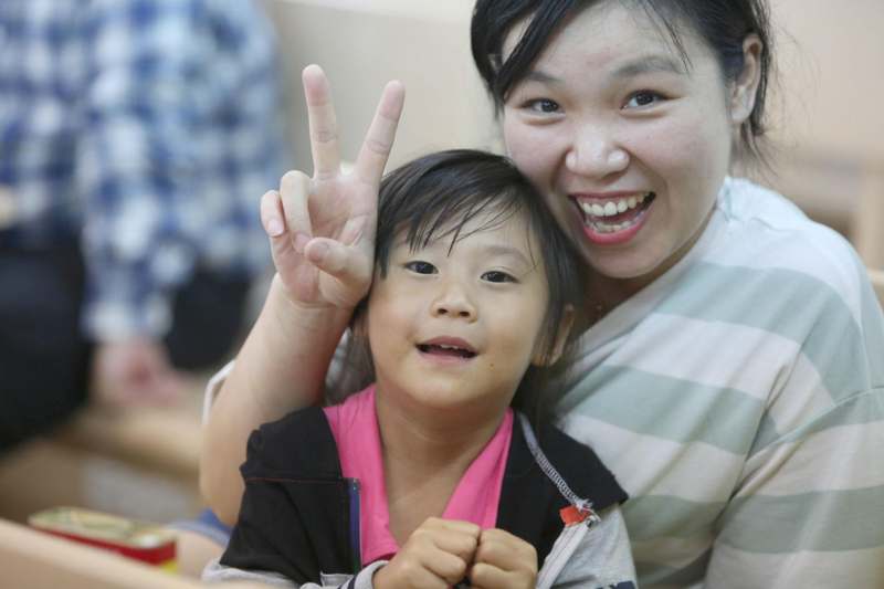 a woman and child holding up a peace sign