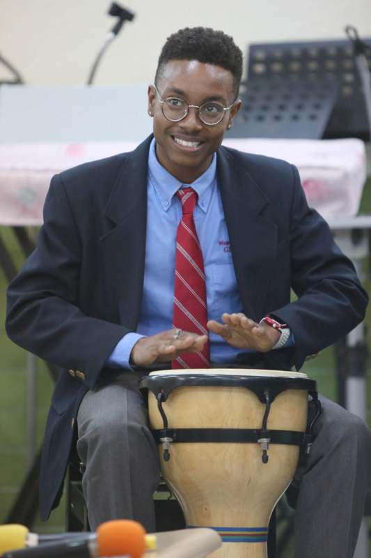 a man in a suit and tie playing a drum