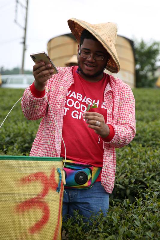 a man wearing a straw hat and holding a cellphone