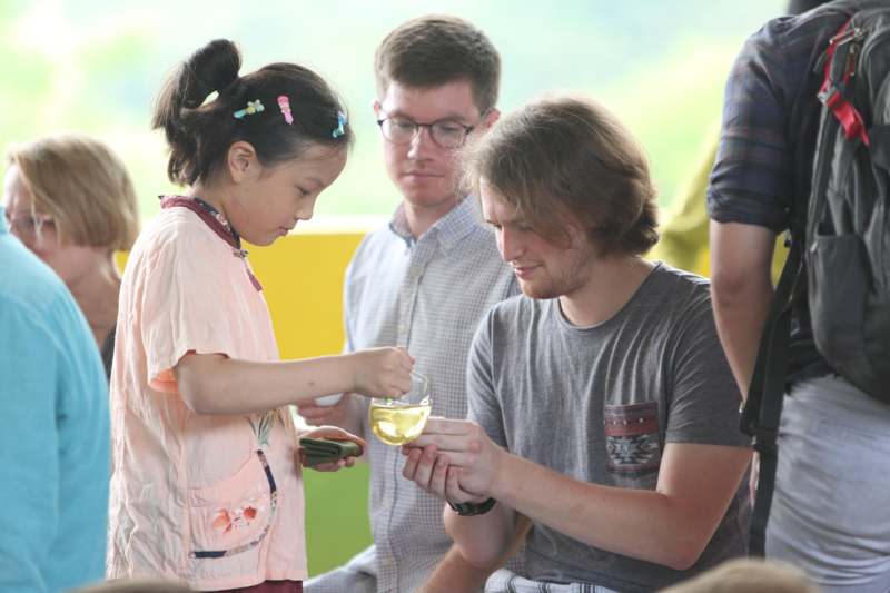 a group of people standing around a child holding a glass of liquid