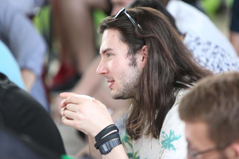 a man with long hair and sunglasses in a white shirt