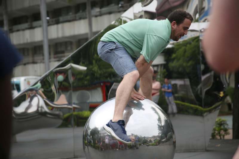 a man balancing on a silver ball