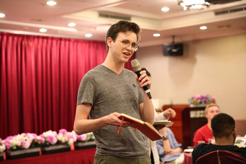 a man holding a microphone and speaking into a book