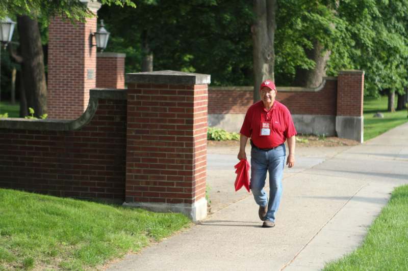 a man in a red shirt walking on a sidewalk