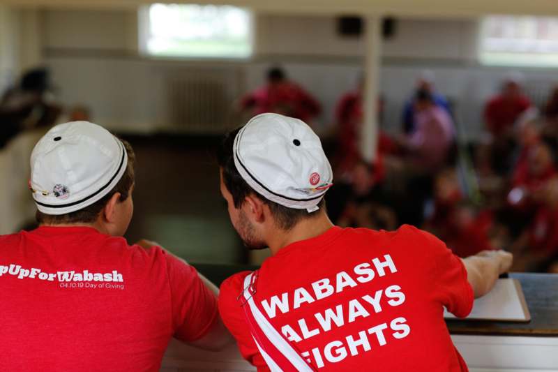 two men wearing red shirts and white hats