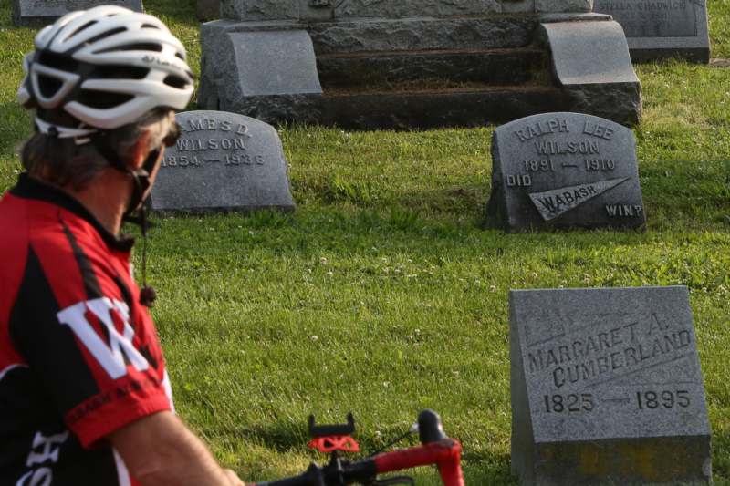 a person wearing a helmet and riding a bike in a cemetery