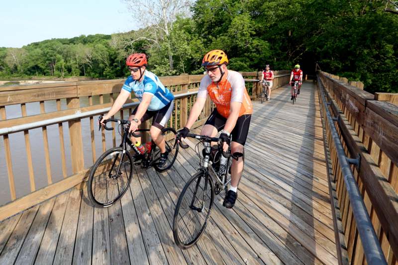 a group of people riding bicycles on a wooden bridge