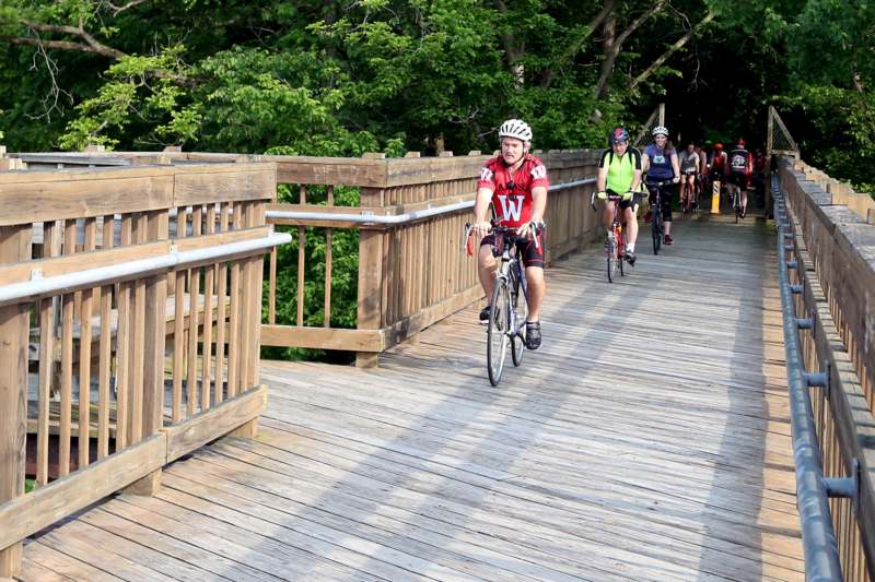 a group of people riding bicycles on a bridge