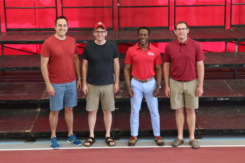 a group of men standing in front of a red wall