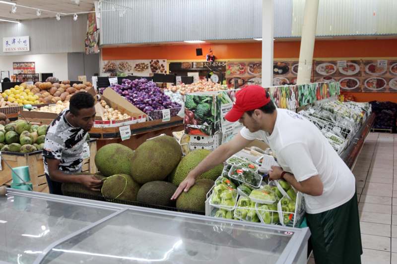 a man looking at a large fruit in a grocery store