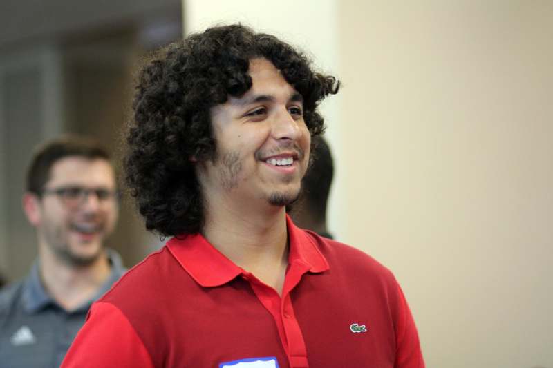 a man with curly hair wearing a red shirt