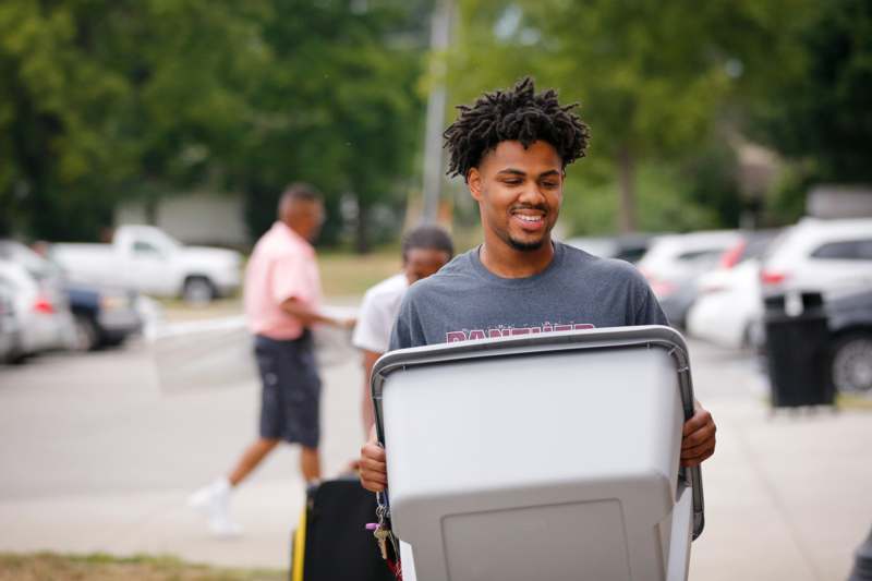 a man carrying a trash can