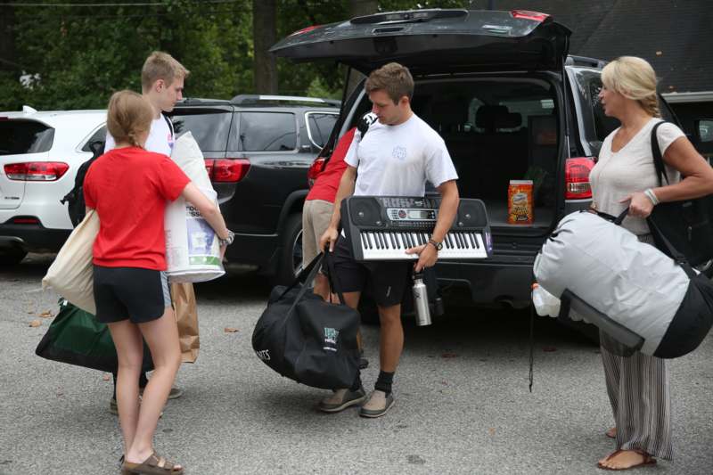 a group of people standing in the back of a car with bags and a piano
