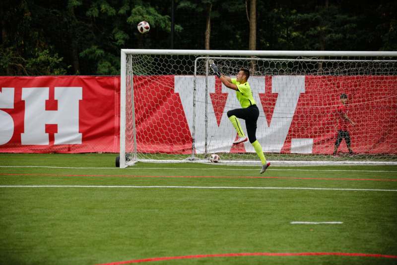 a man in a green shirt jumping to catch a football ball