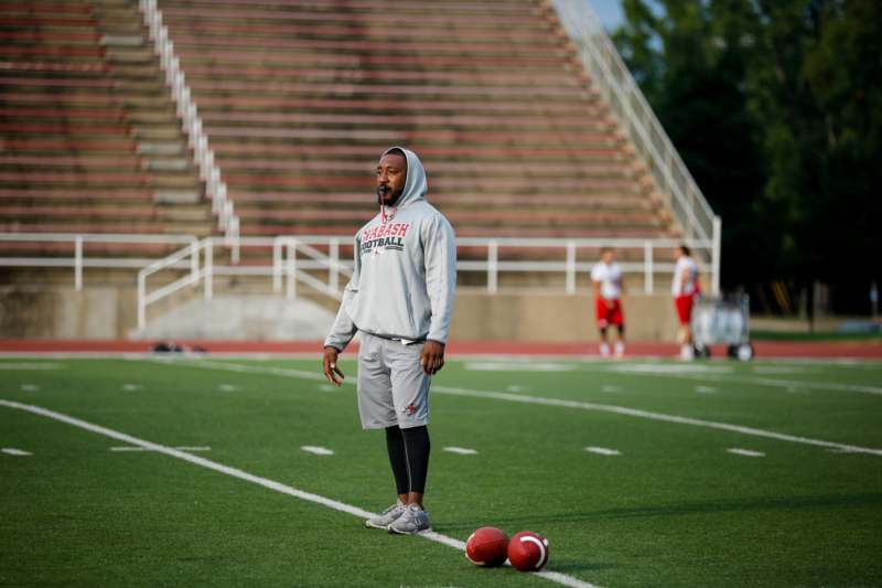 a man standing on a football field with two balls