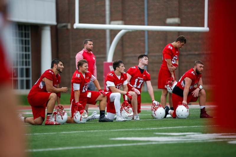 a group of men kneeling on a field with football helmets