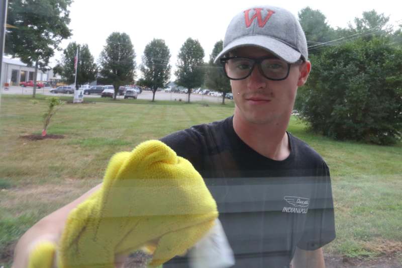 a man wearing glasses and a hat cleaning a window