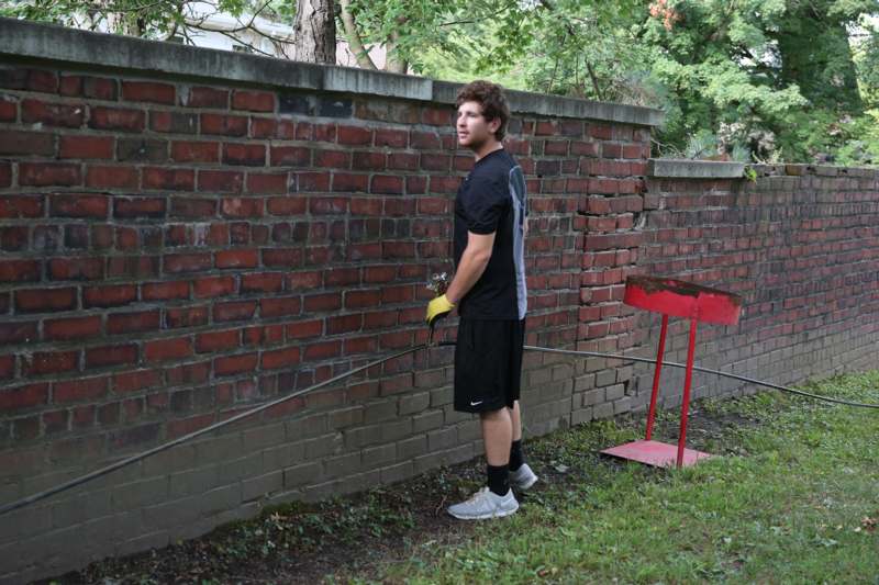 a man standing next to a brick wall