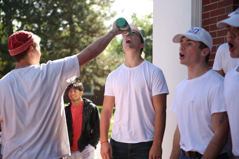 a group of men drinking from a green cup