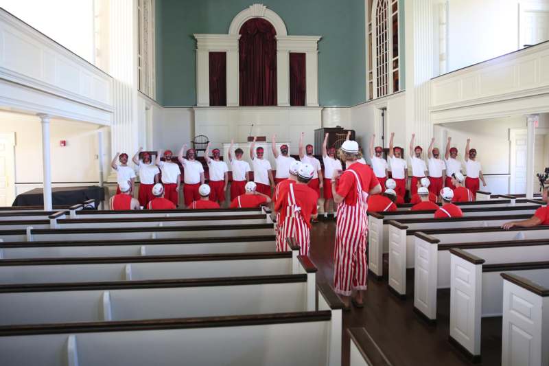 a group of people in red and white striped uniforms in a church