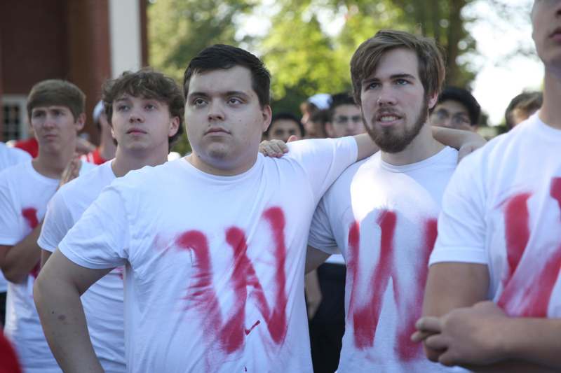 a group of men wearing white shirts with red letters on them