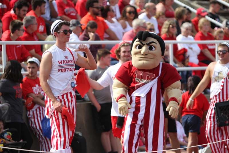 a man in a red and white striped shirt and a mascot in a crowd